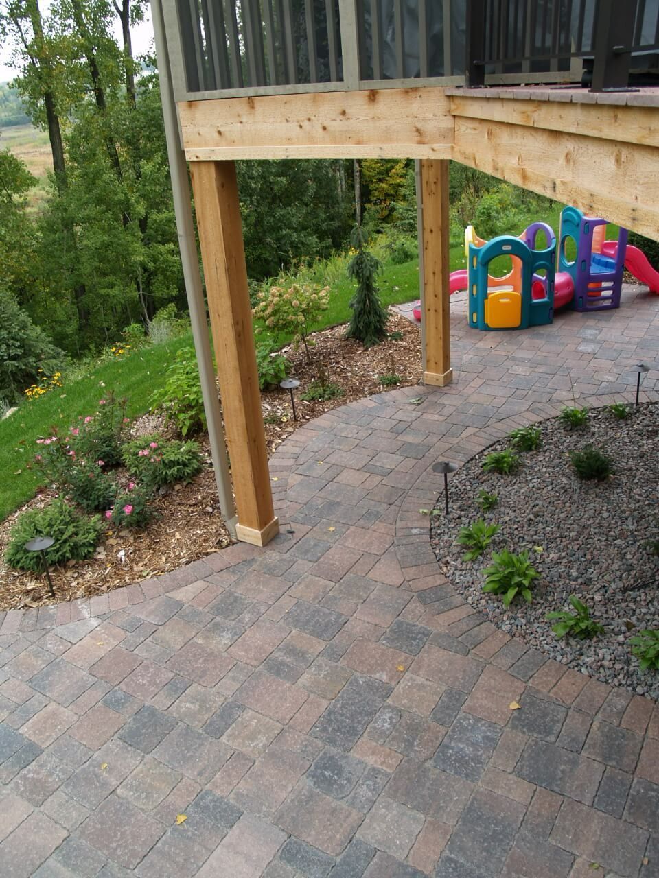 A patio with a wooden deck and a playground in the background.