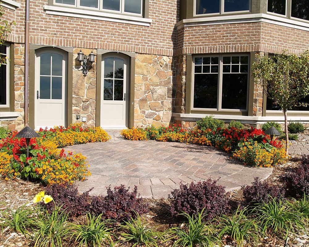 A brick house with a patio and flowers in front of it