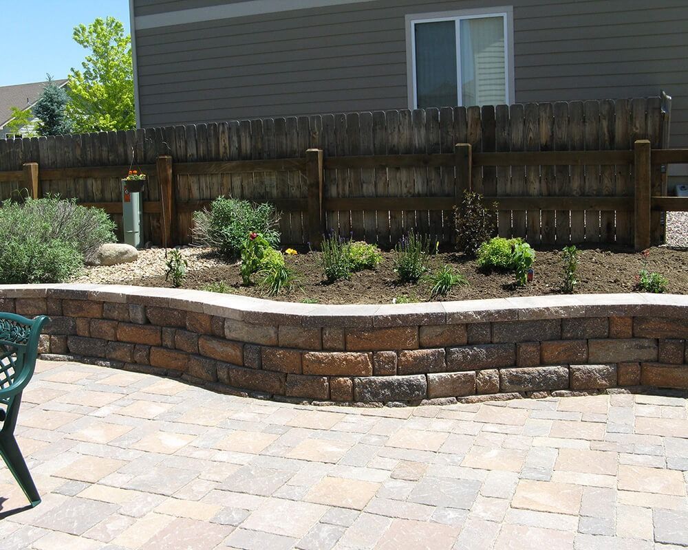 A wooden fence surrounds a brick wall in front of a house