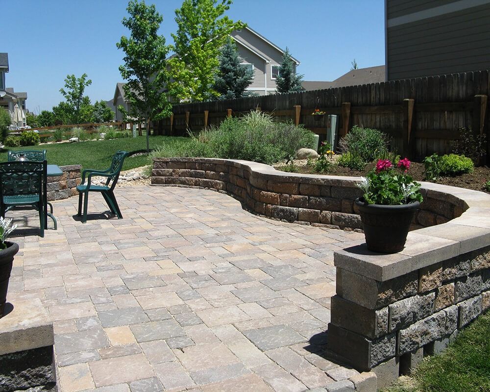 A patio with a brick wall and chairs and flowers