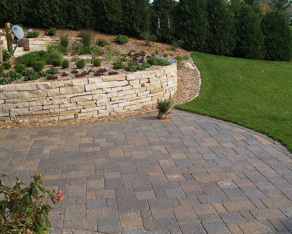 A brick walkway with a stone wall in the background