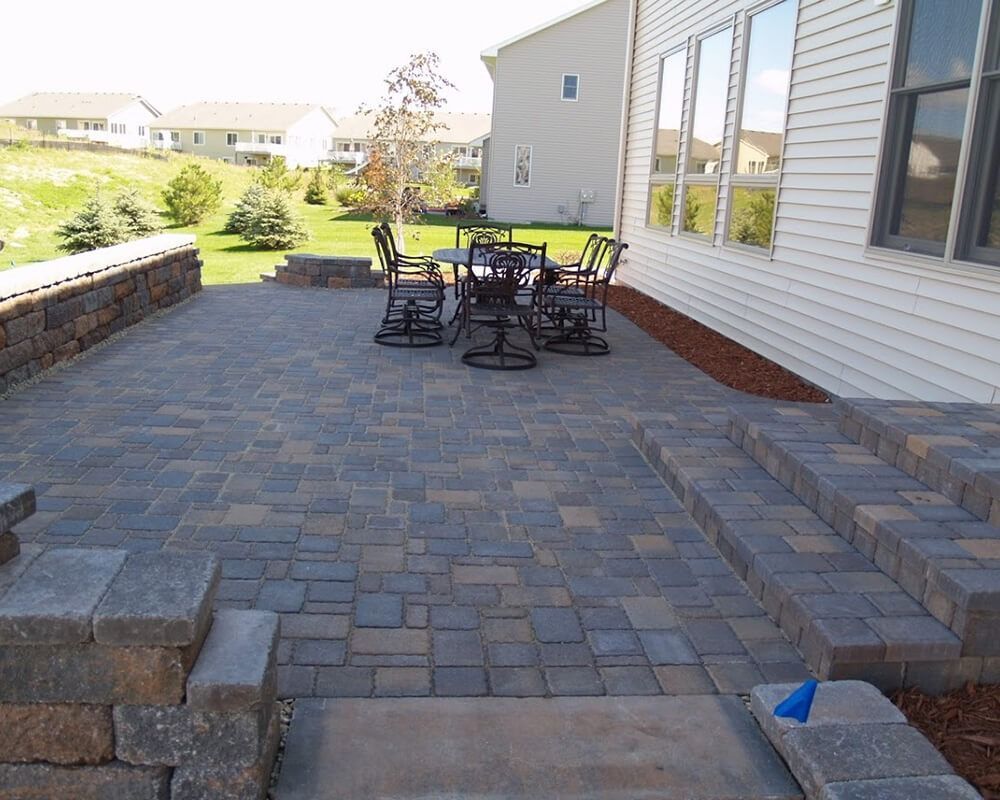 A patio with a table and chairs in front of a house
