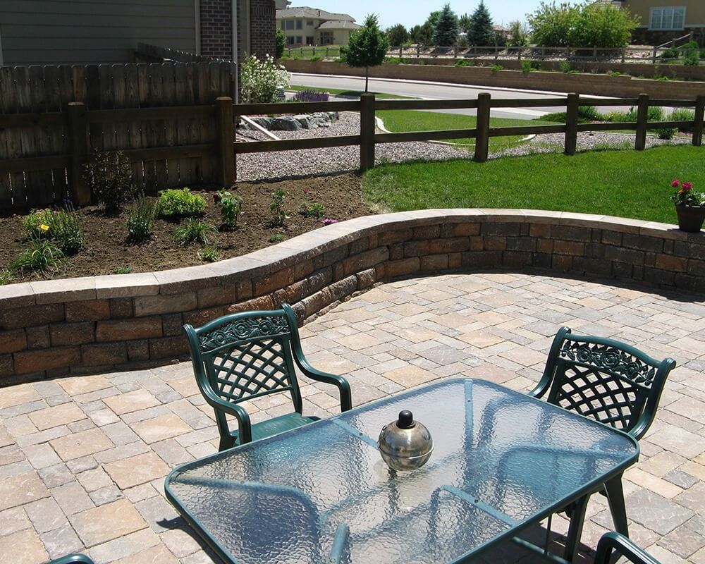 A table and chairs on a patio with a fence in the background