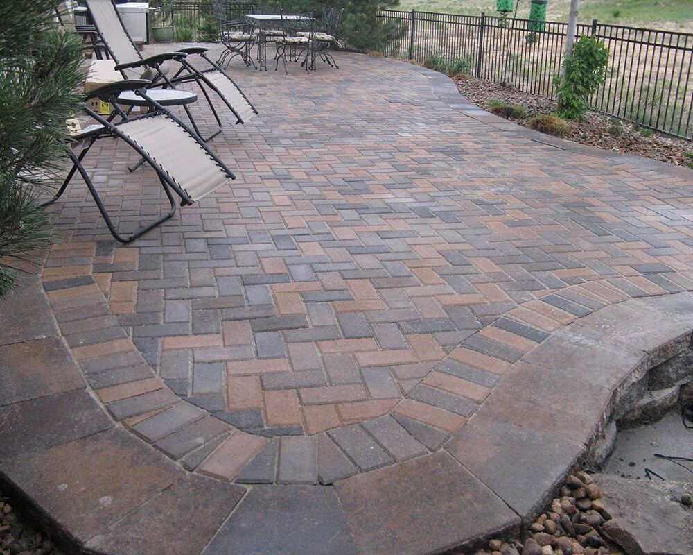 A brick patio with chairs and a table in the background