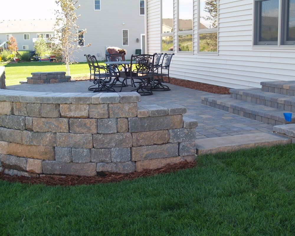 A patio with a table and chairs in front of a house