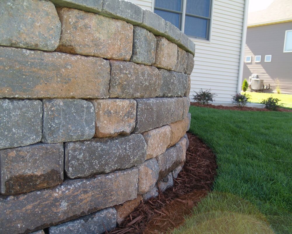 A brick wall with a house in the background