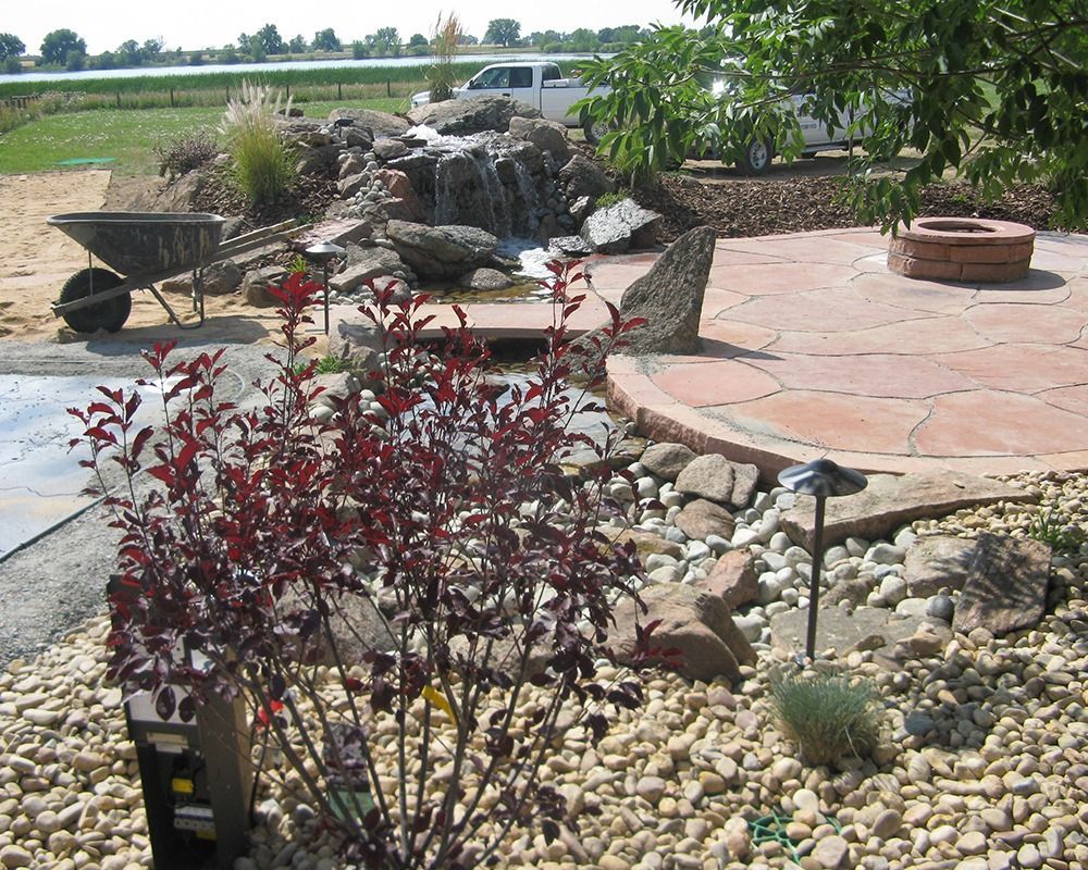 A rock garden with a waterfall and a fire pit