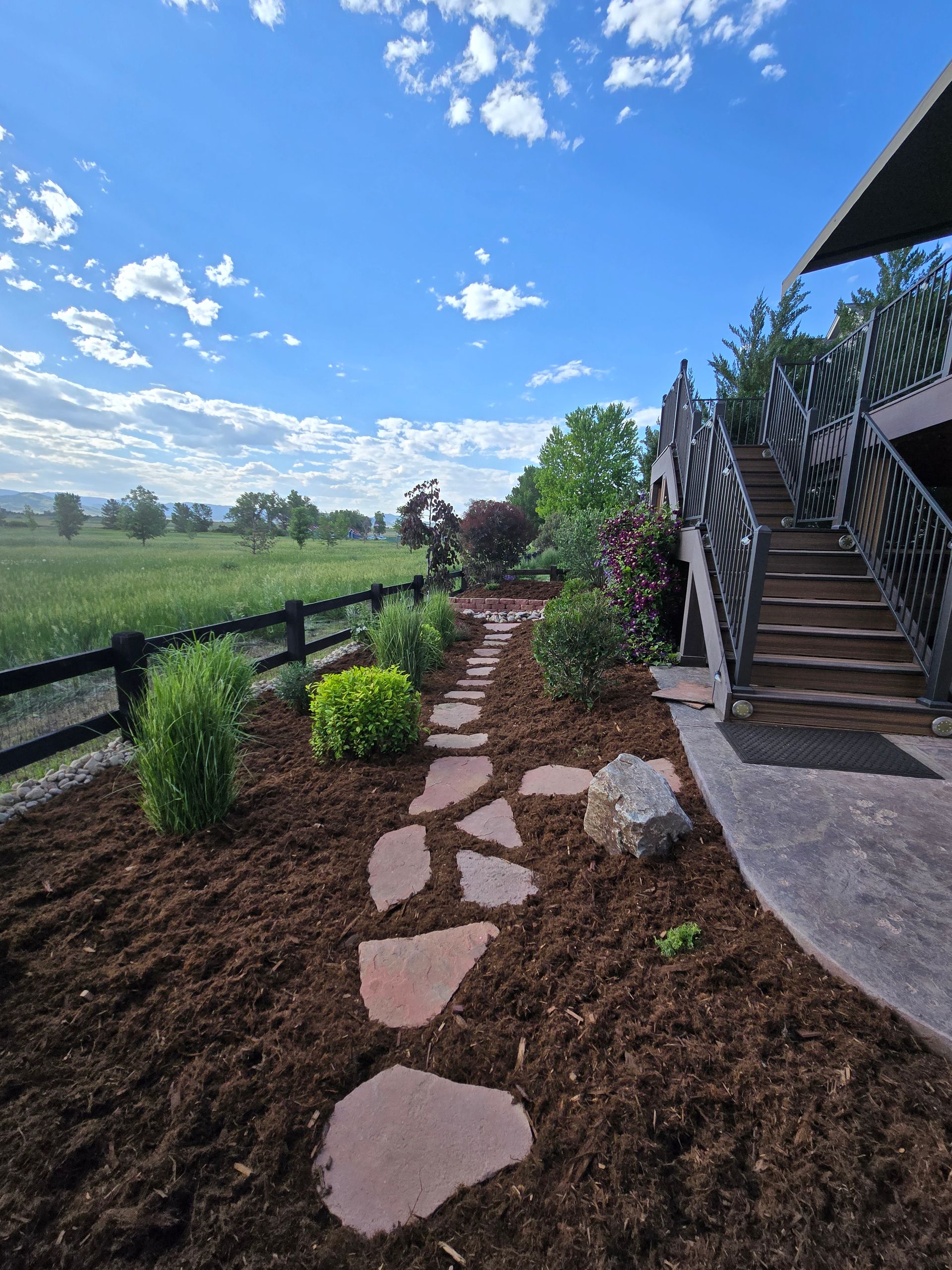 A stone walkway leading to a house with stairs leading up to it.