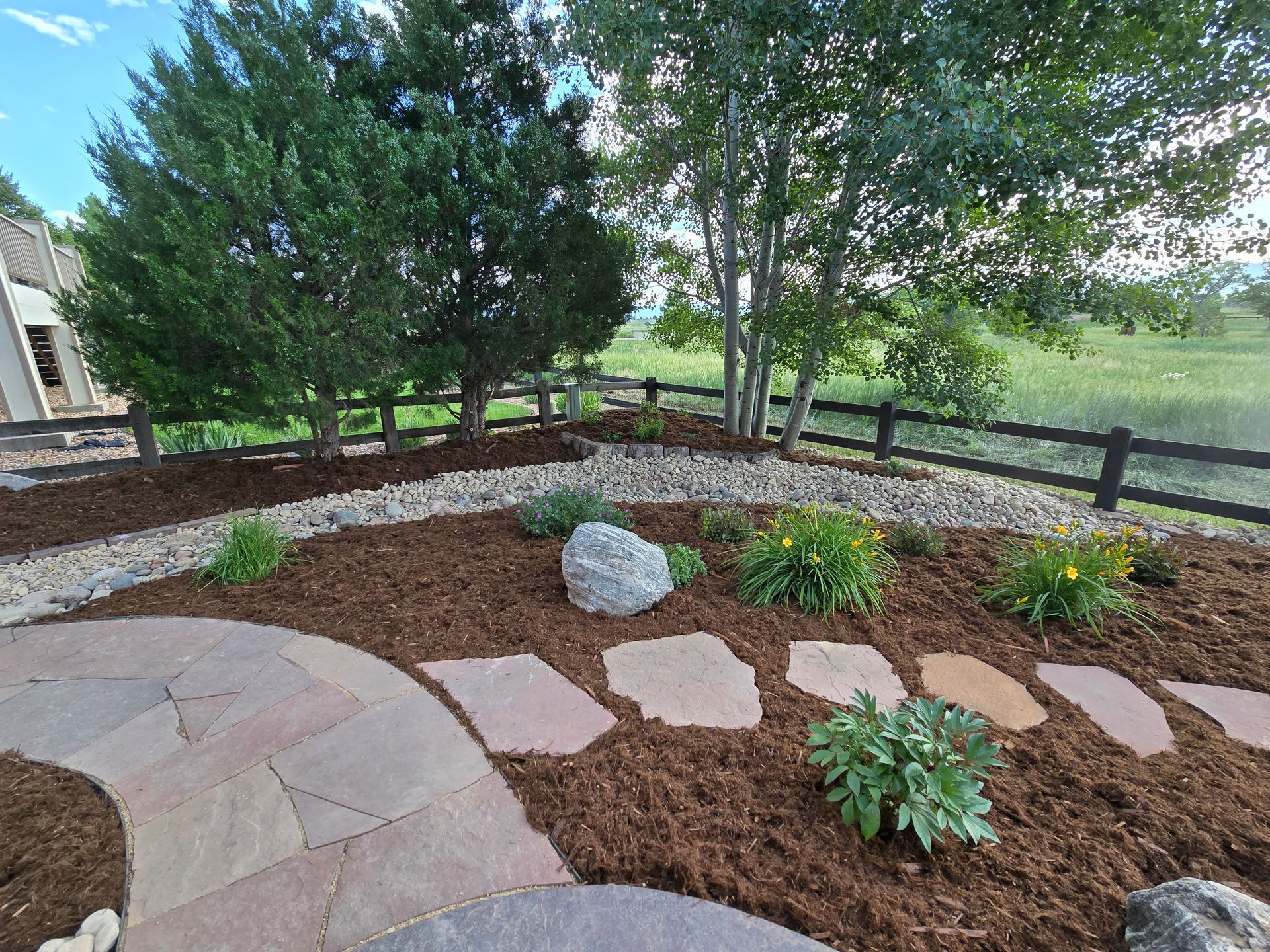 There is a fence in the background and a patio in the foreground.