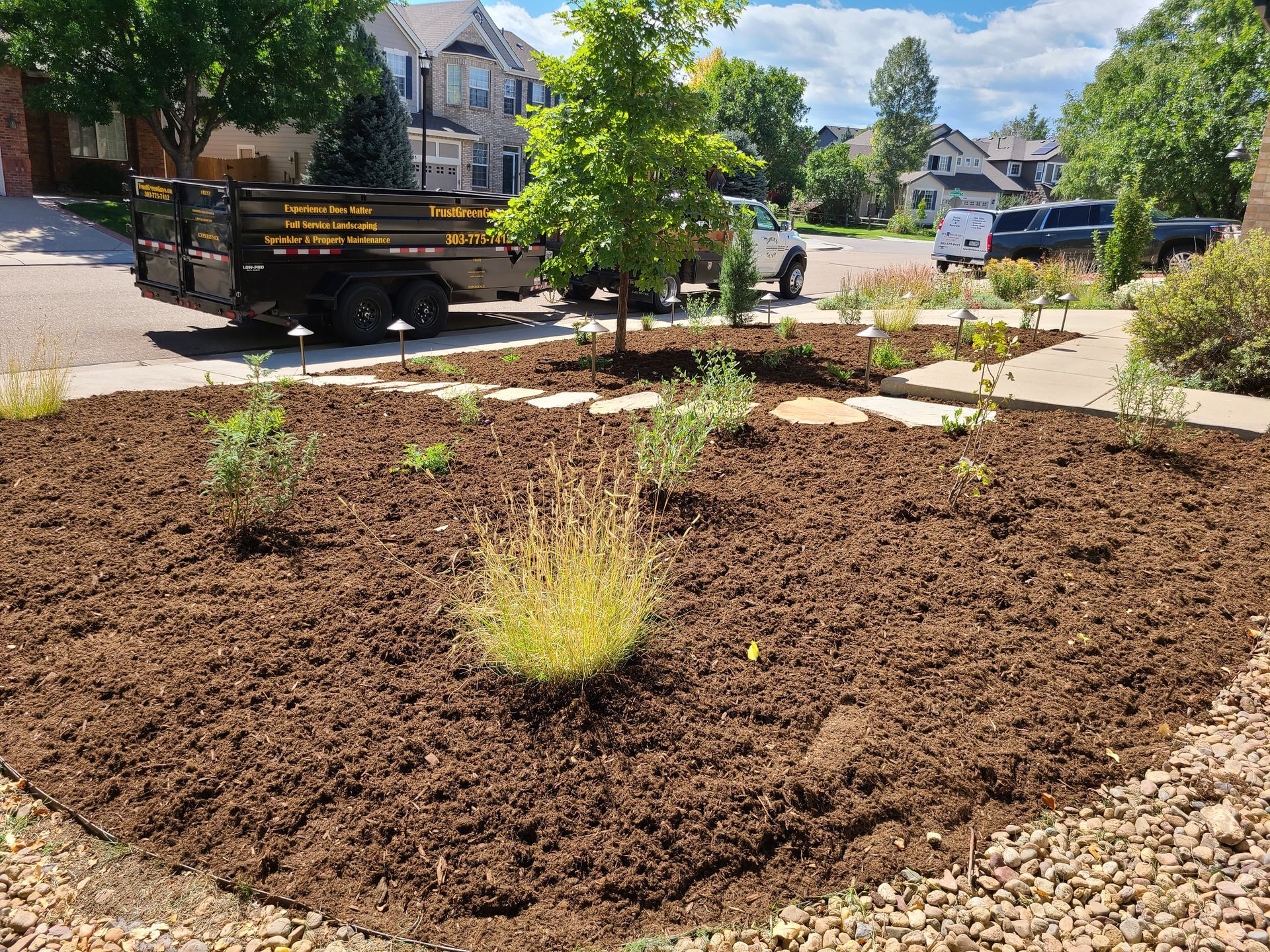 A truck is parked in a driveway next to a pile of mulch