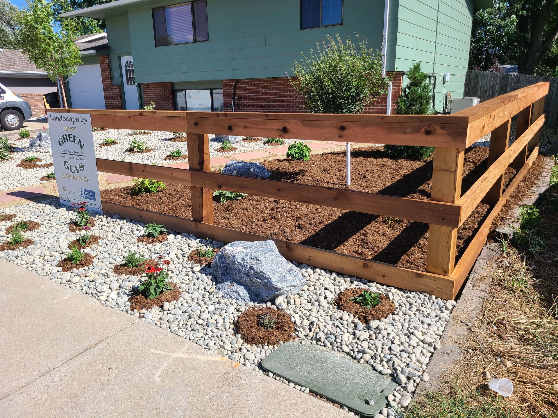 A wooden fence is surrounding a garden in front of a house