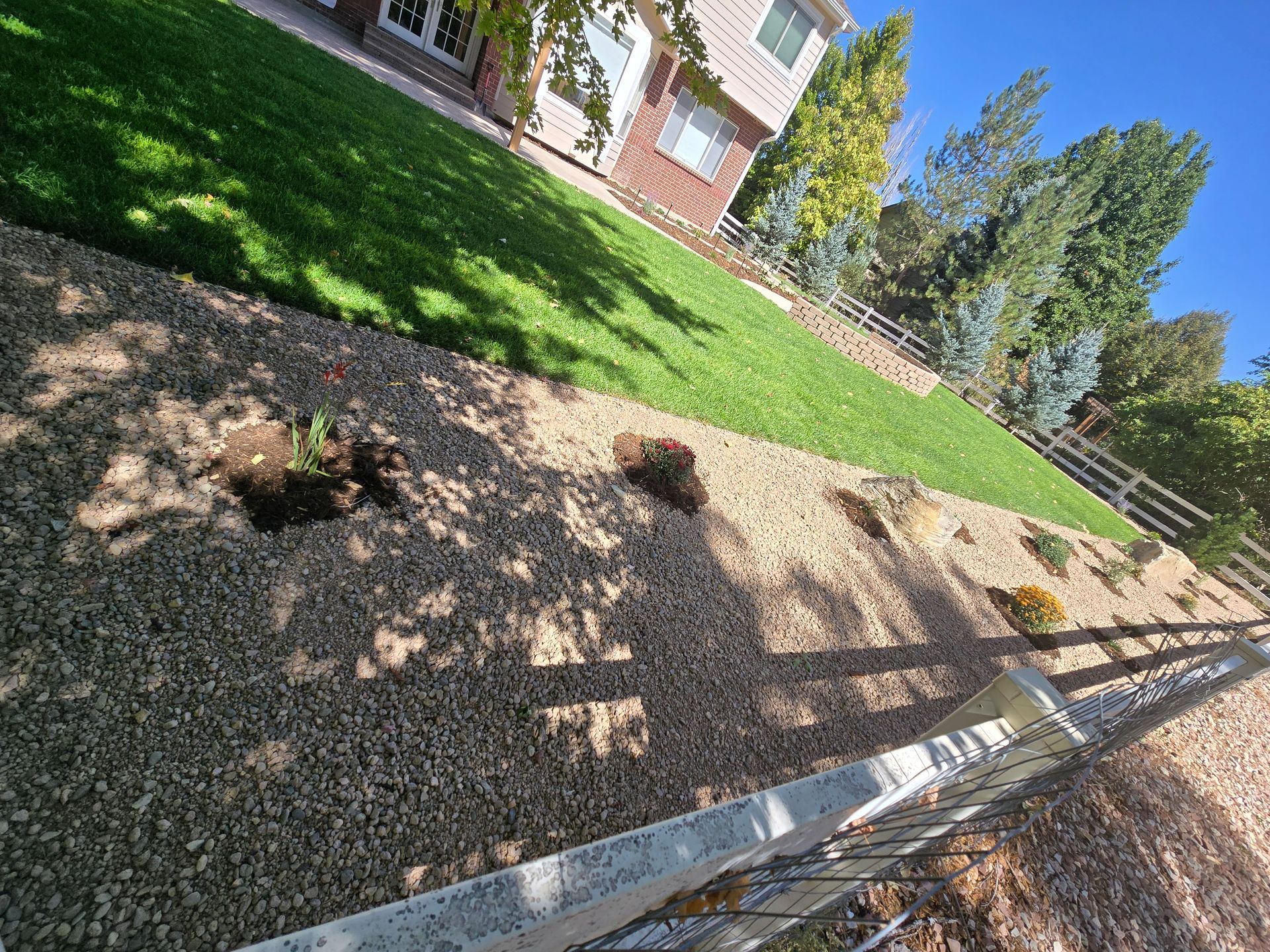 A fence is surrounding a lush green lawn in front of a house