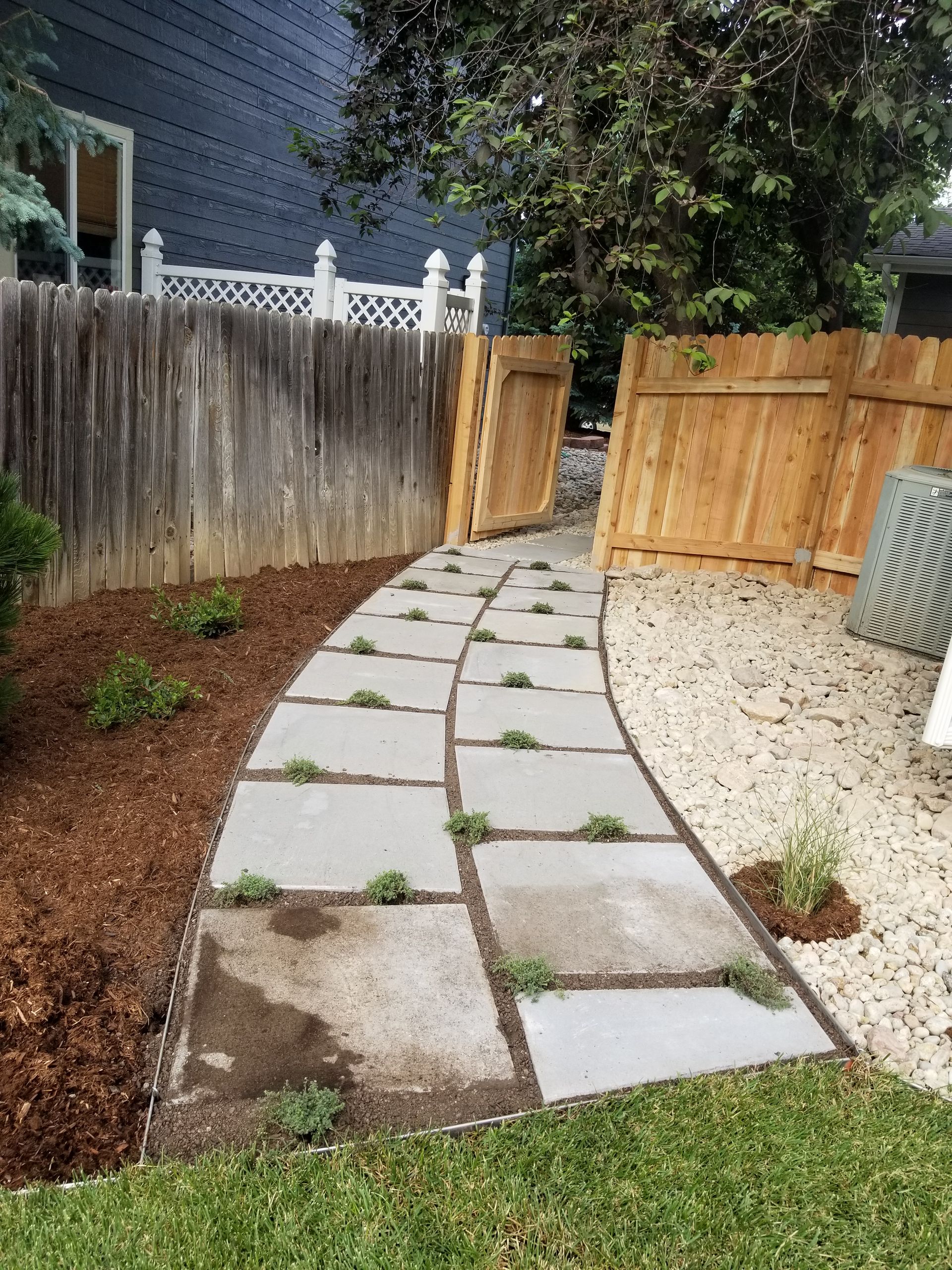 A stone walkway leading to a wooden fence