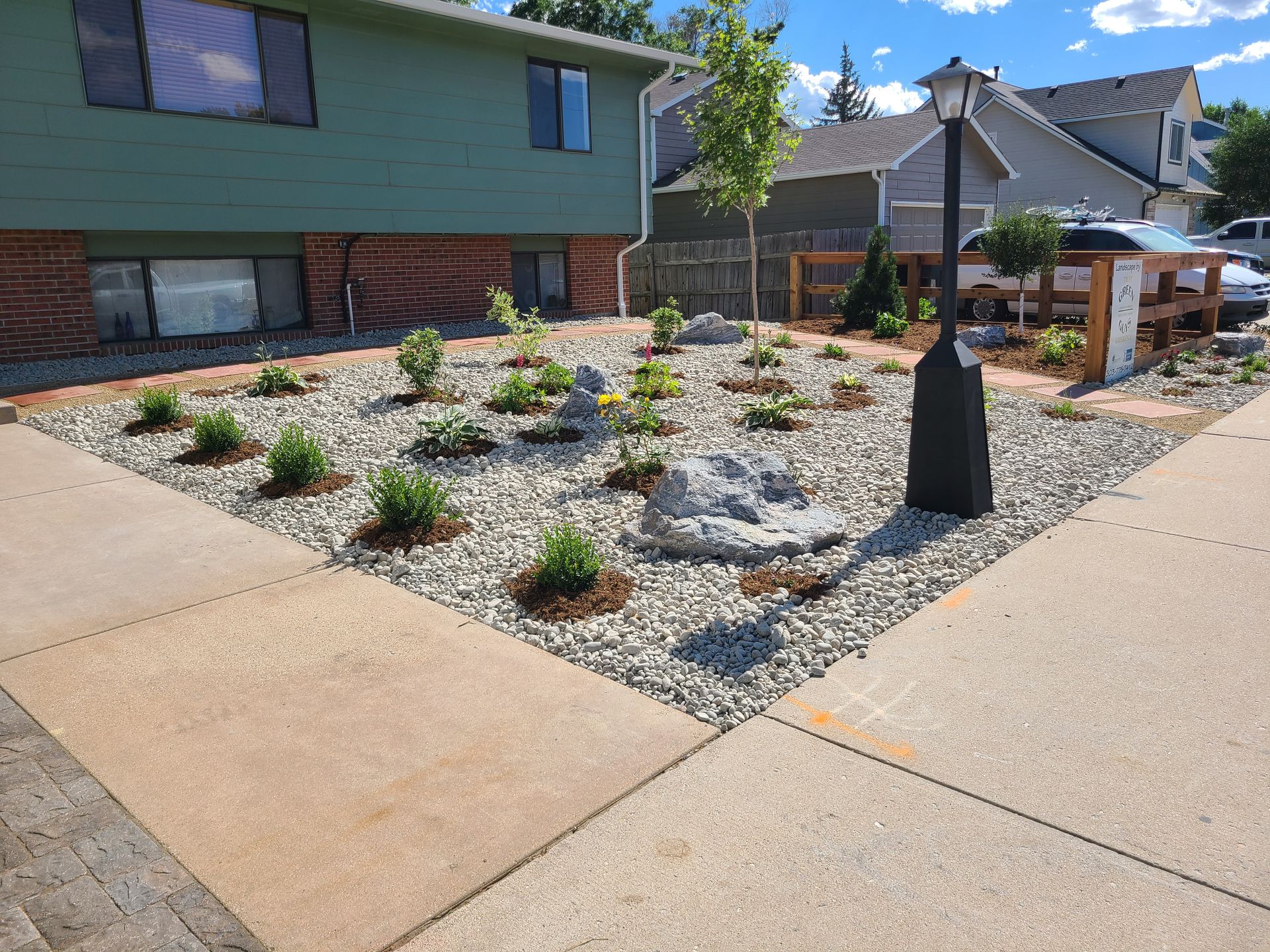 A yard with a lot of rocks and plants in front of a house