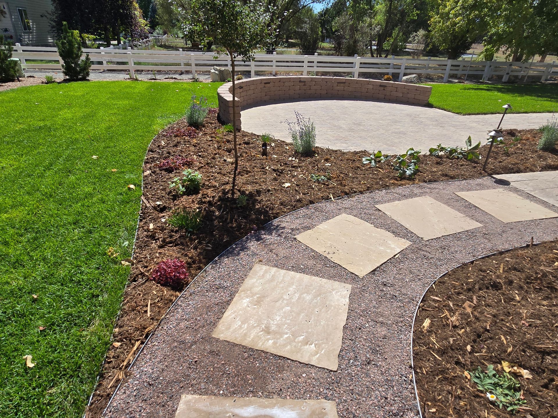 A walkway leading to a patio in a backyard with a fence in the background