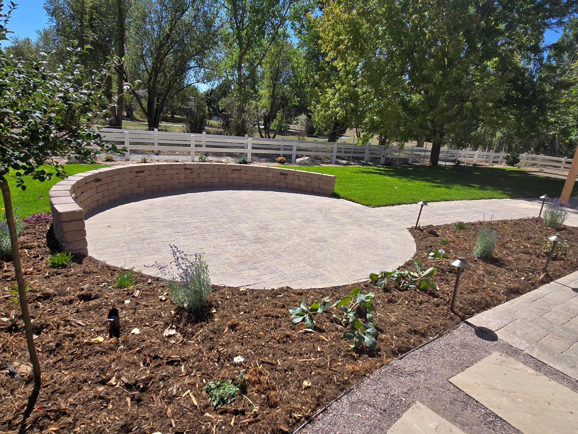 A circular patio with a brick wall and a fence in the background
