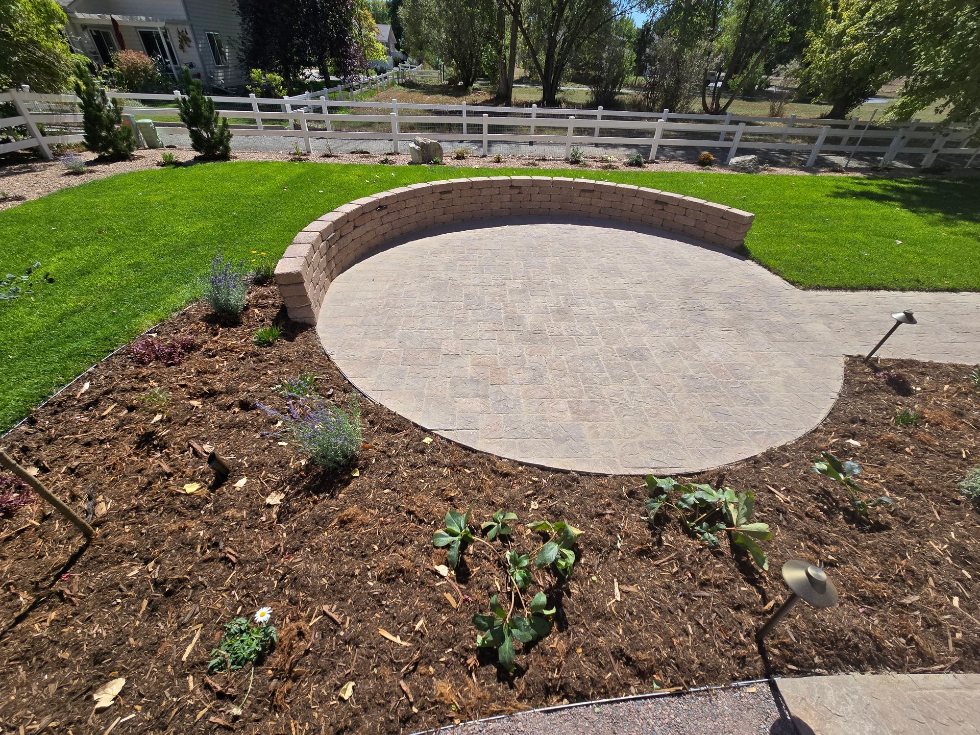 There is a circular patio in the middle of the yard