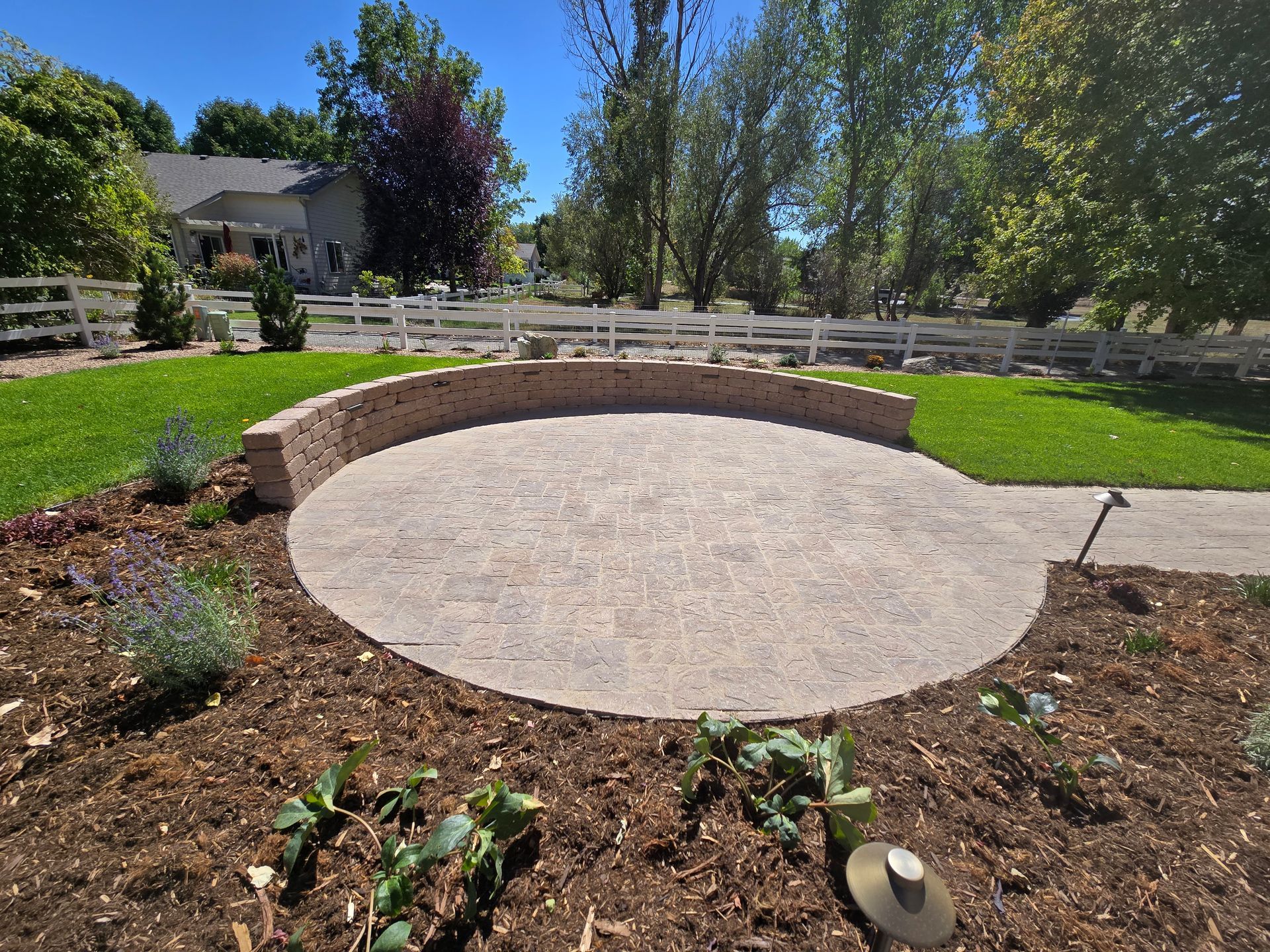 A circular patio with a white fence in the background