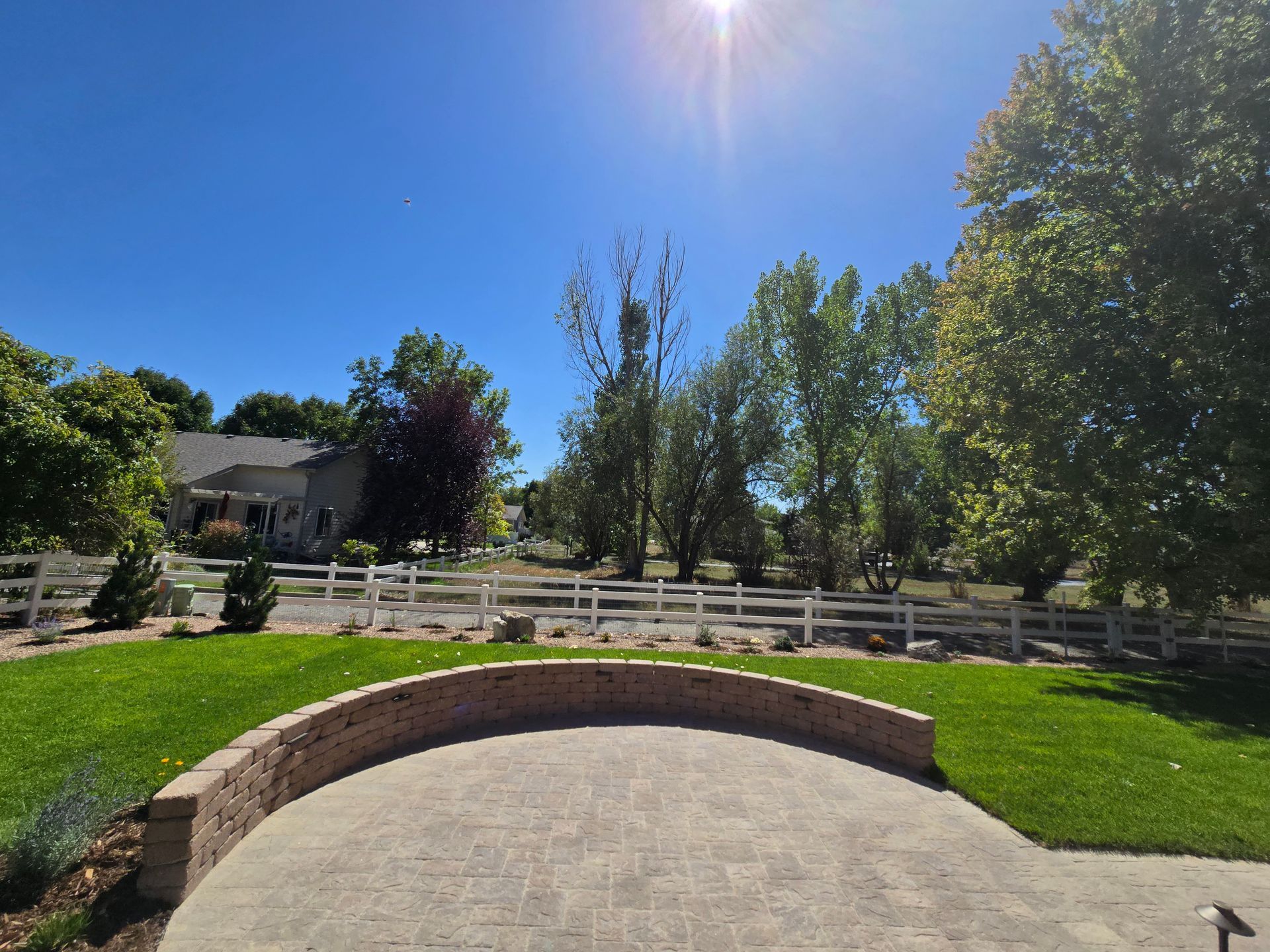 A patio with a white fence in the background and a house in the background