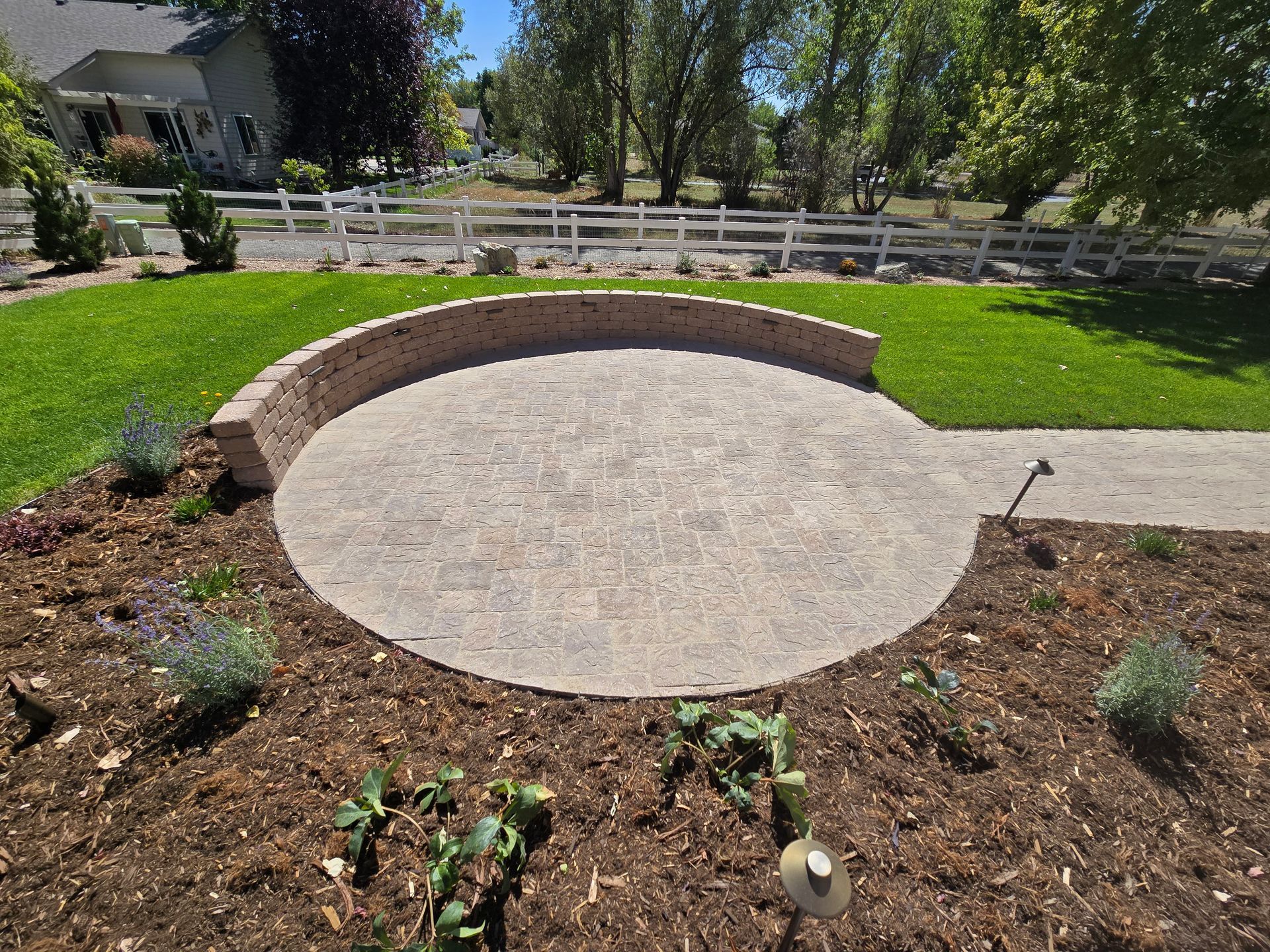 There is a circular patio in the middle of the yard