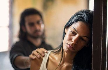 A man is putting his hand on a woman's shoulder