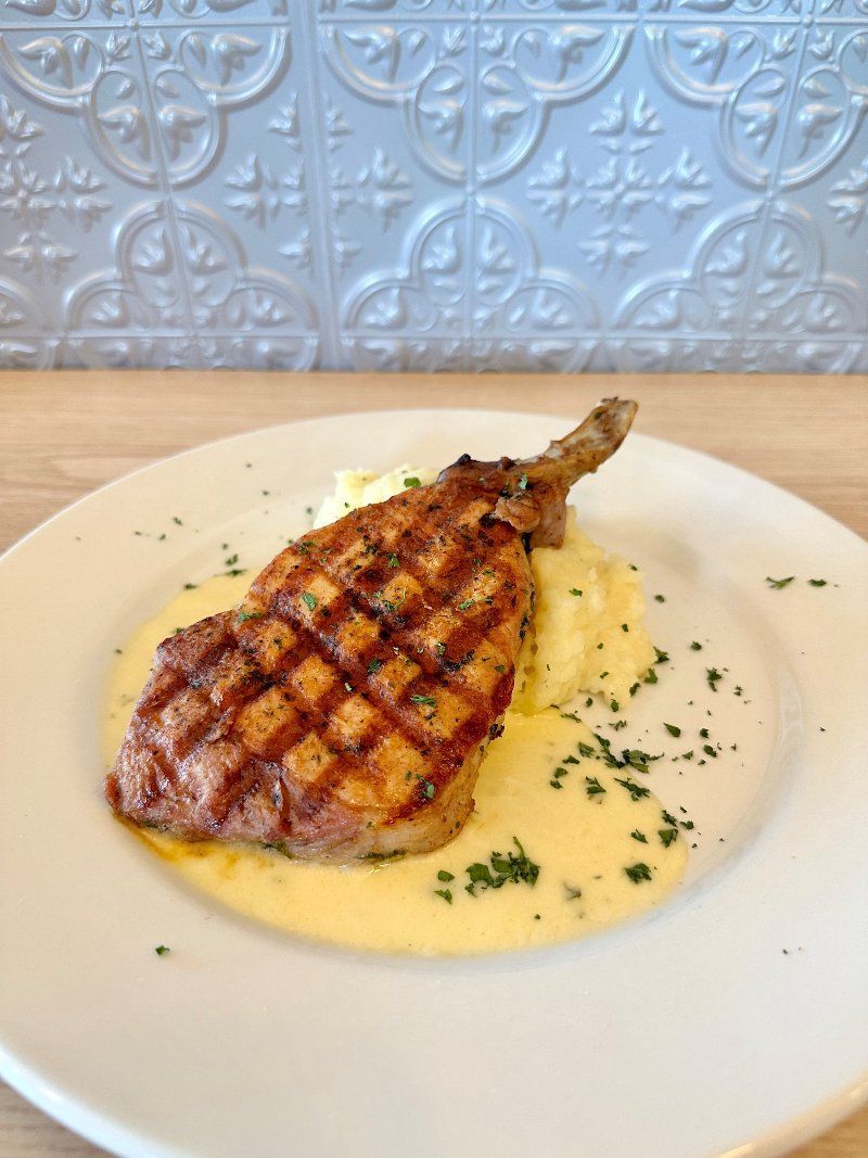 A white plate topped with a piece of meat and mashed potatoes.