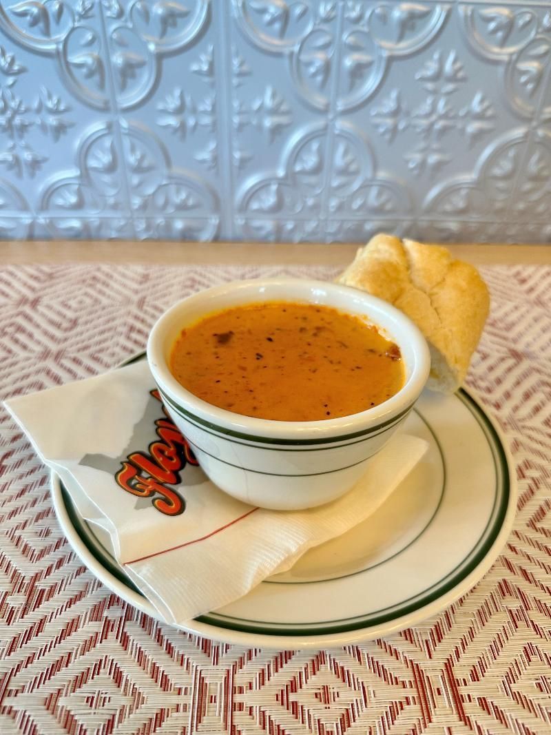A bowl of soup and a piece of bread on a plate