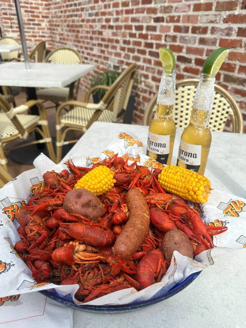 A bowl of crawfish and corn on the cob on a table.