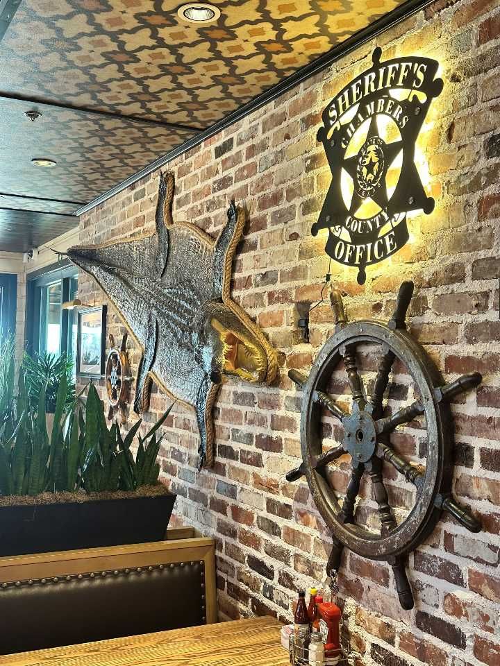 A brick wall with a sheriff 's office sign and a steering wheel on it.