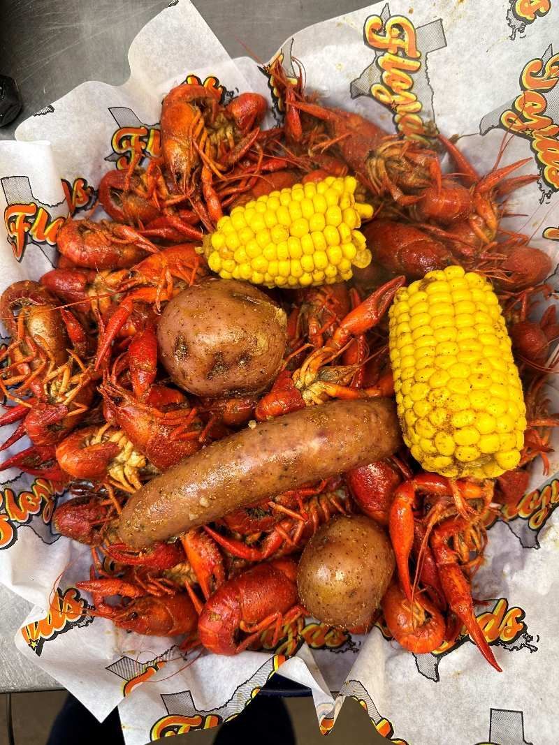 A basket filled with crawfish , corn on the cob , potatoes and shrimp.