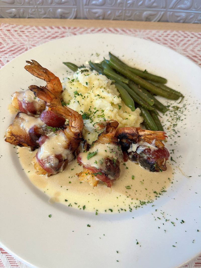 A white plate topped with shrimp , mashed potatoes and green beans.