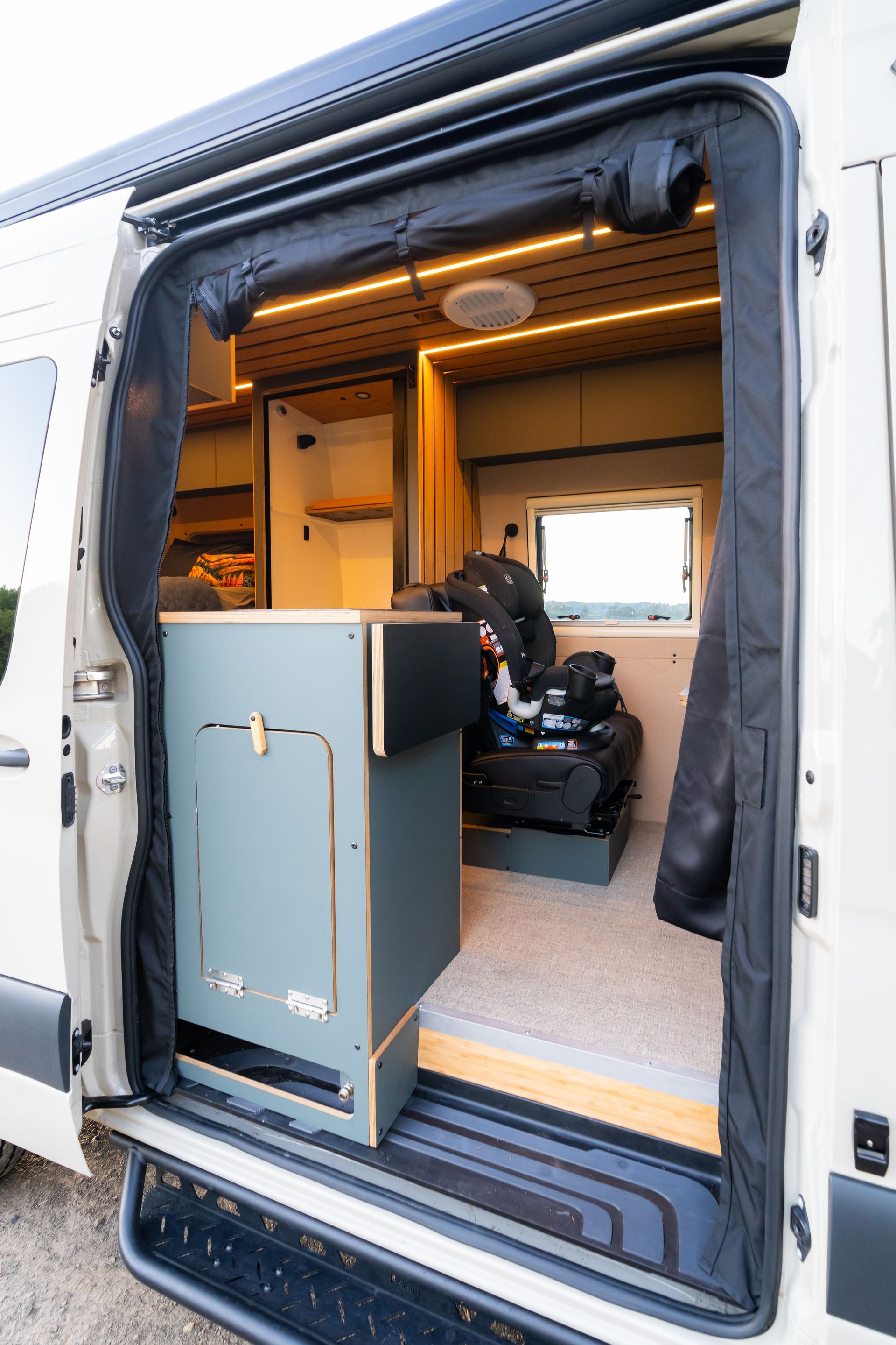 Open van converted into a compact camper with a blue cabinet and interior seating.
