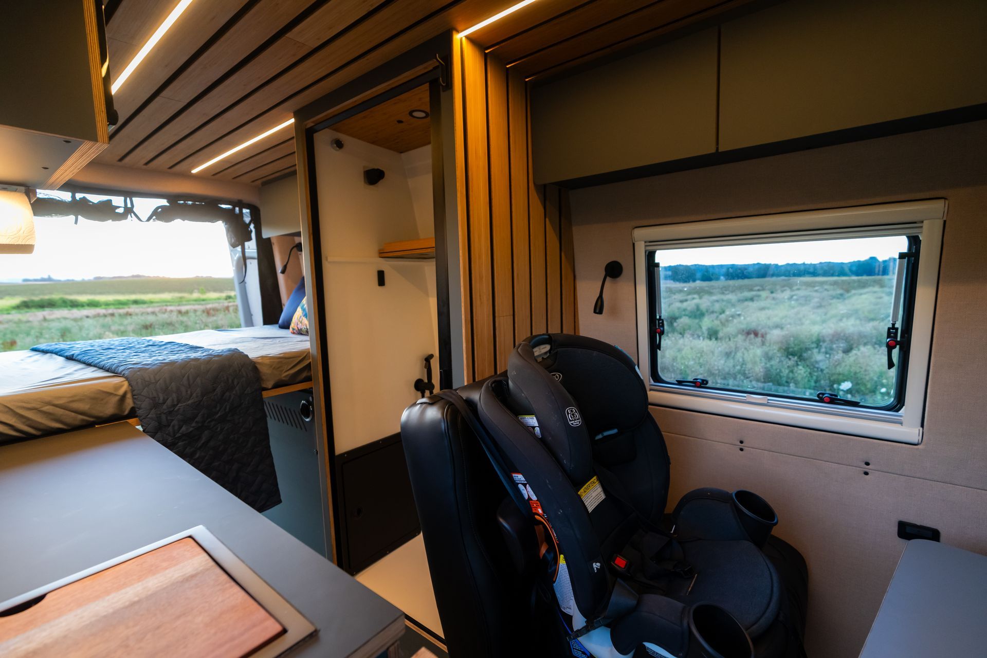 Compact camper van interior with two front seats and a window view of the countryside