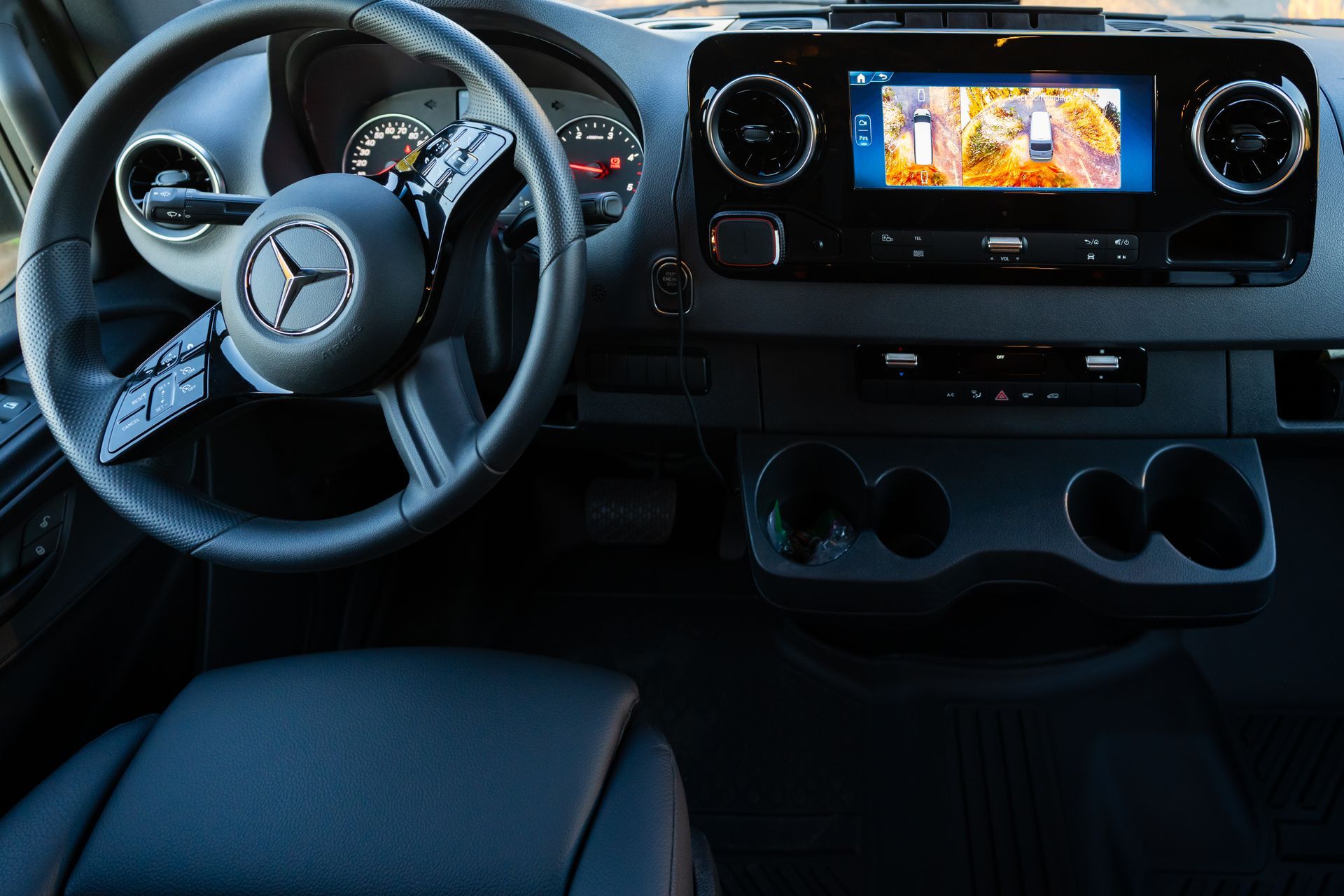 Car interior with Mercedes steering wheel, digital dashboard, and center infotainment screen.