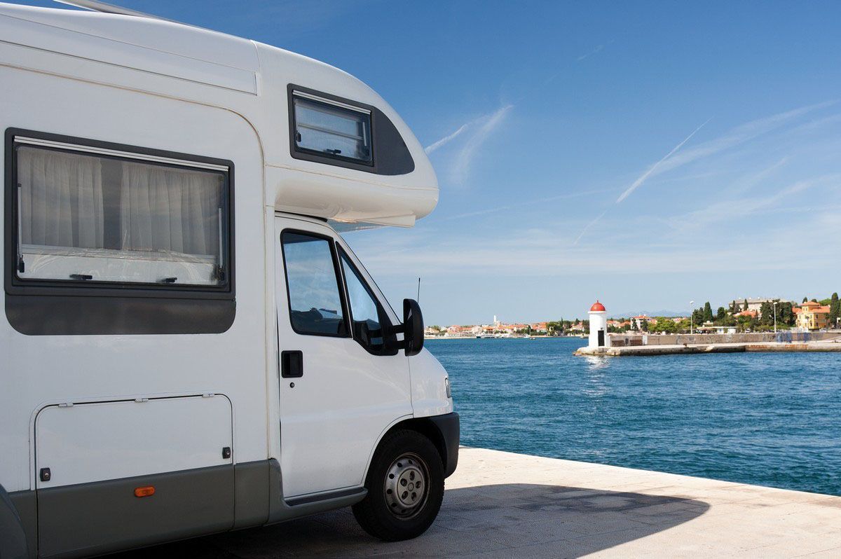 White camper van parked by the seaside under a clear blue sky