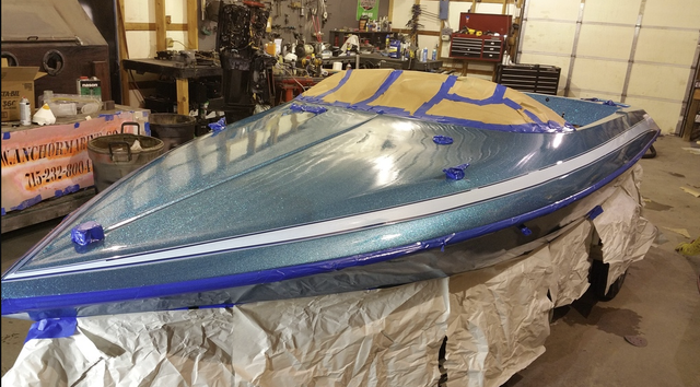 A blue and white boat is sitting on a table in a garage.