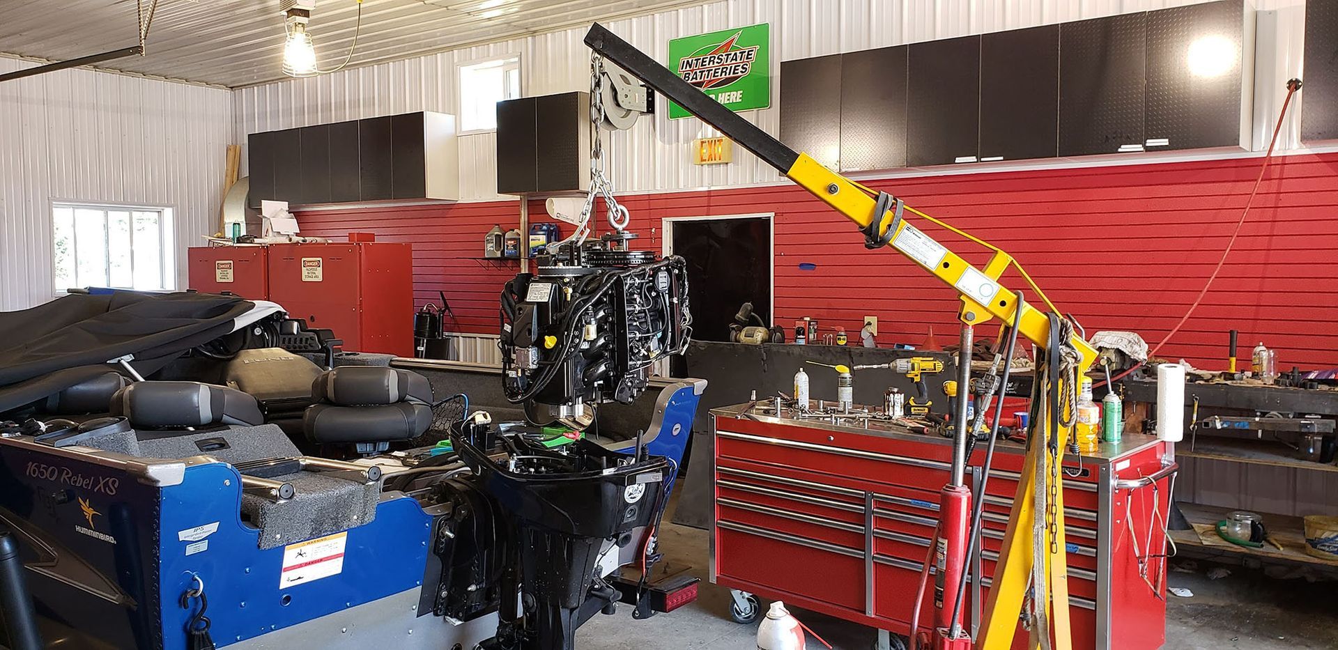 There is a crane in the middle of the room in a garage.