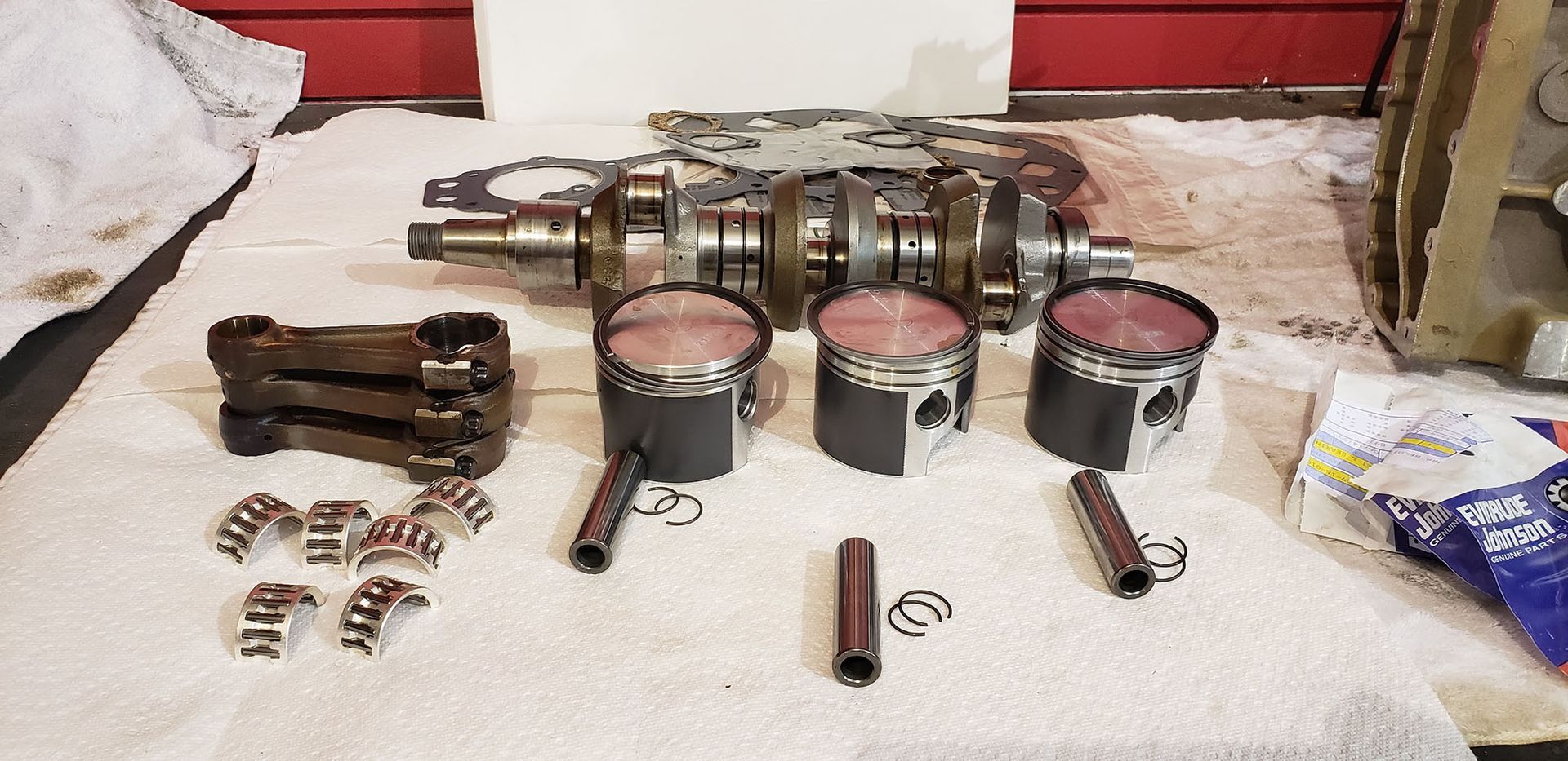 A crankshaft and pistons are sitting on a towel on a table.
