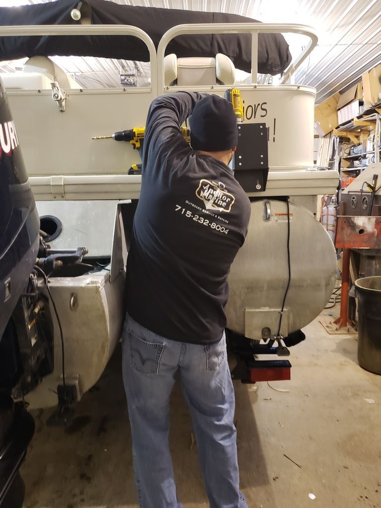 A man is working on a pontoon boat in a garage.