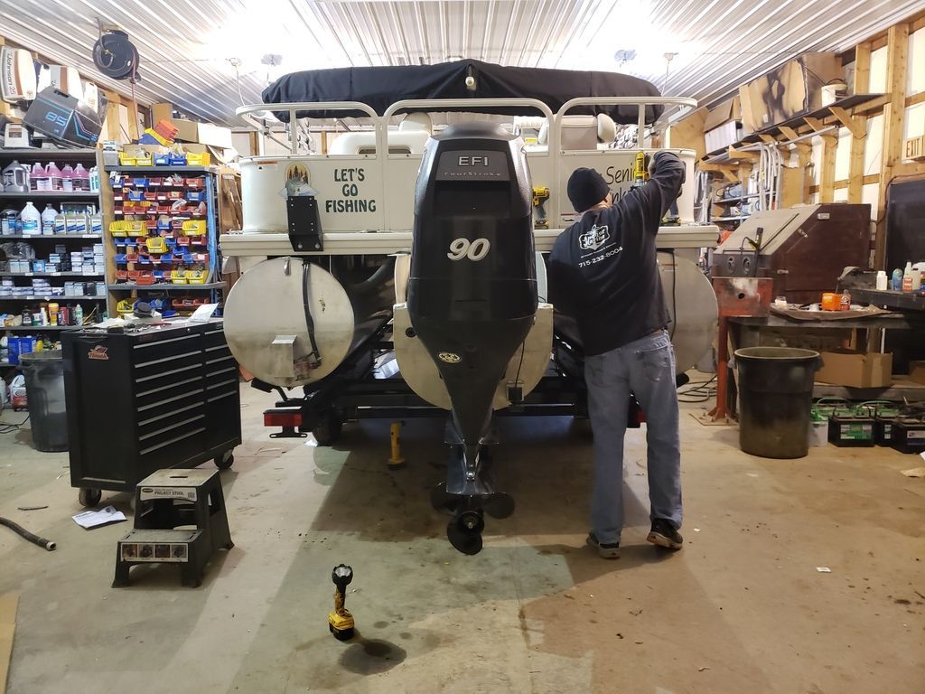 A man is working on a pontoon boat in a garage.