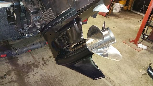 A boat engine is sitting on the floor in a garage.