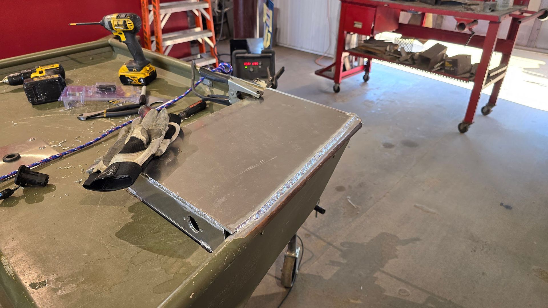 A table with tools and a drill on it in a garage.