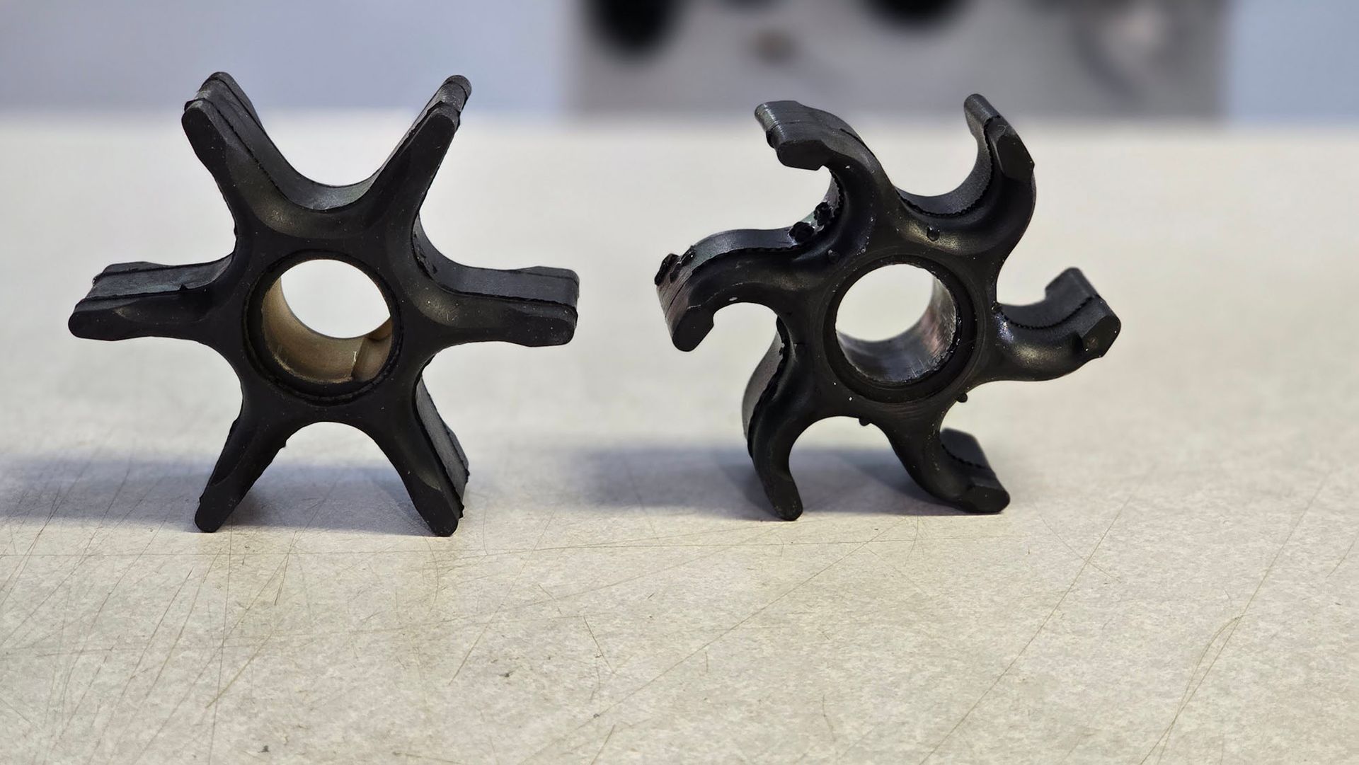 Two black rubber pieces are sitting on a white surface