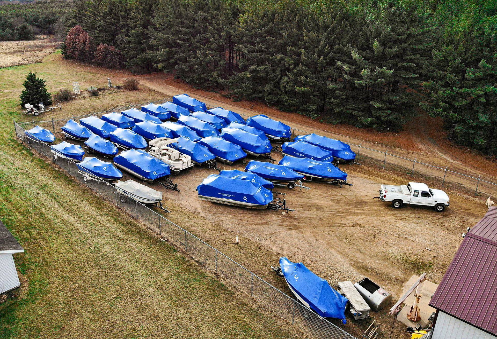 An aerial view of a lot of blue boats and trailers in a field.