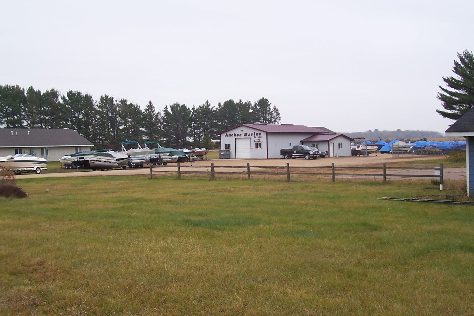 A fence surrounds a grassy field with a garage in the background