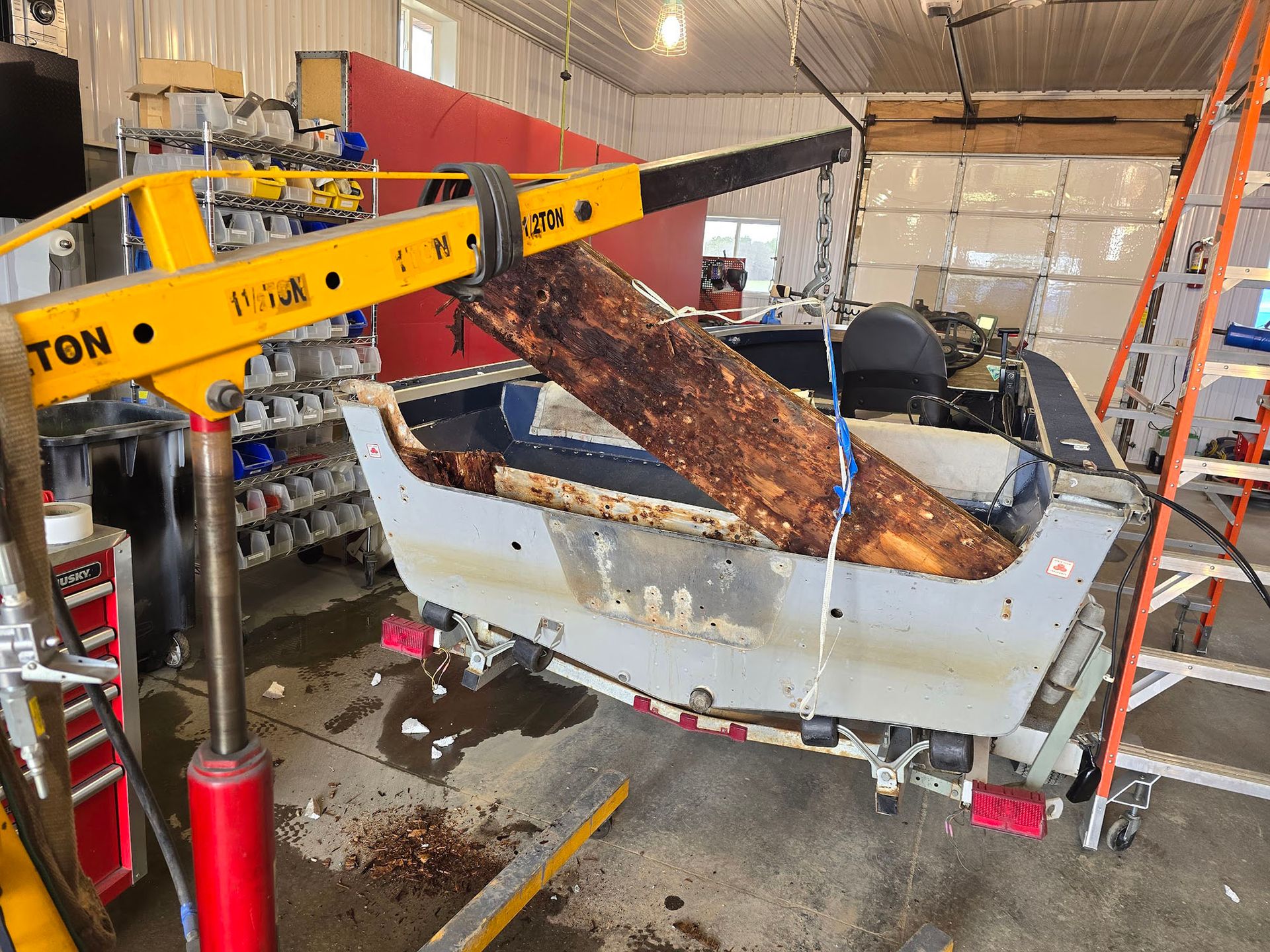 A boat is being lifted by a crane in a garage.