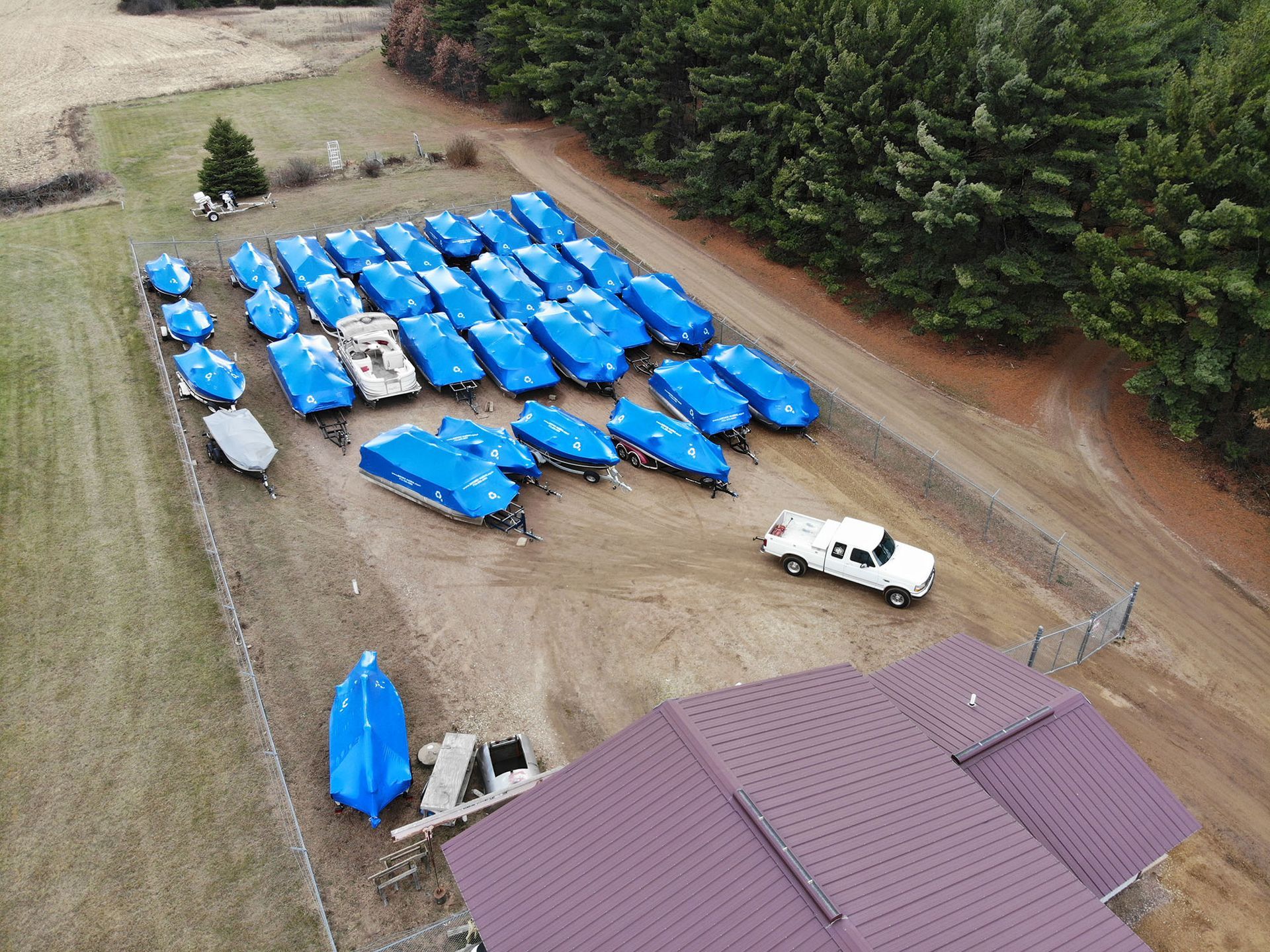 An aerial view of a lot of boats covered in blue tarps.