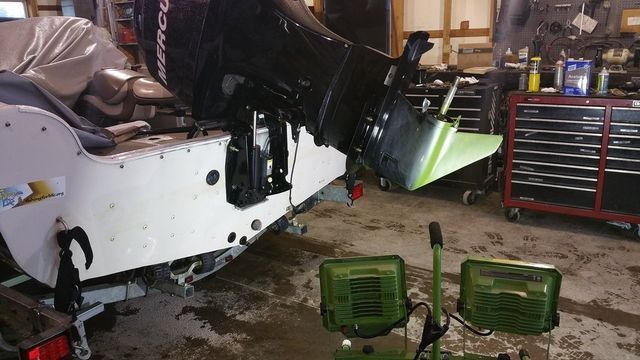 A boat with a mercury outboard motor is in a garage.