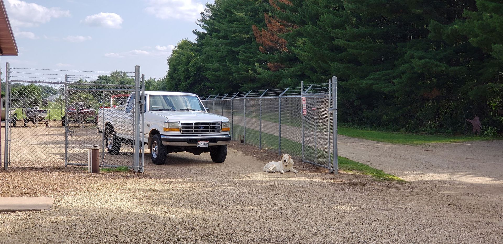 A white truck is parked in front of a chain link fence.
