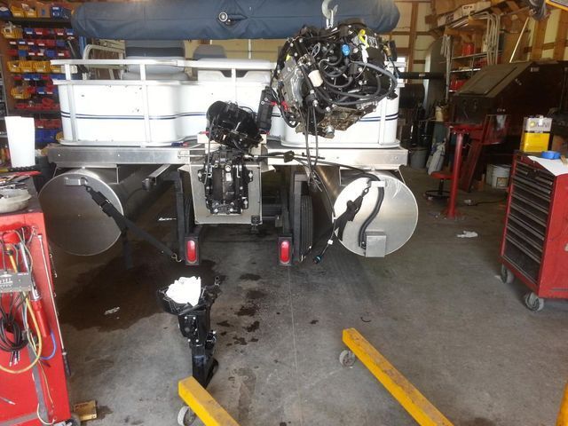 A boat with the engine removed is being worked on in a garage